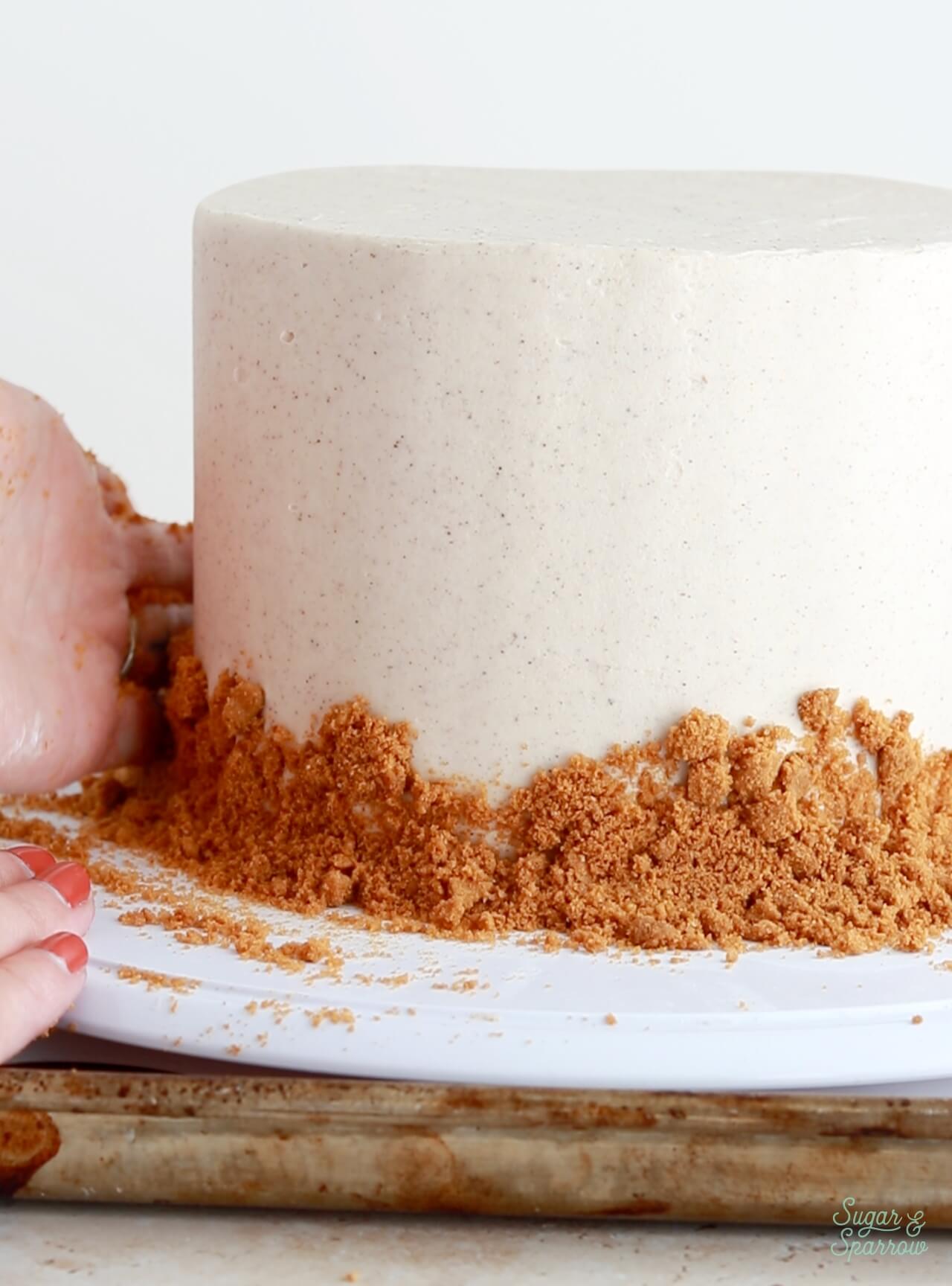 adding biscoff cookie crumbs onto a cake