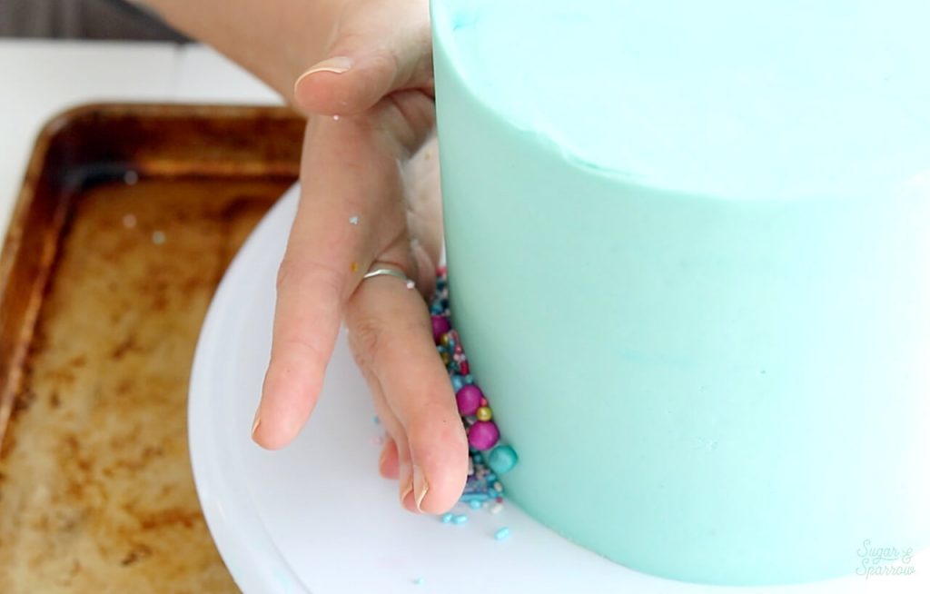 adding sprinkles to the side of cake