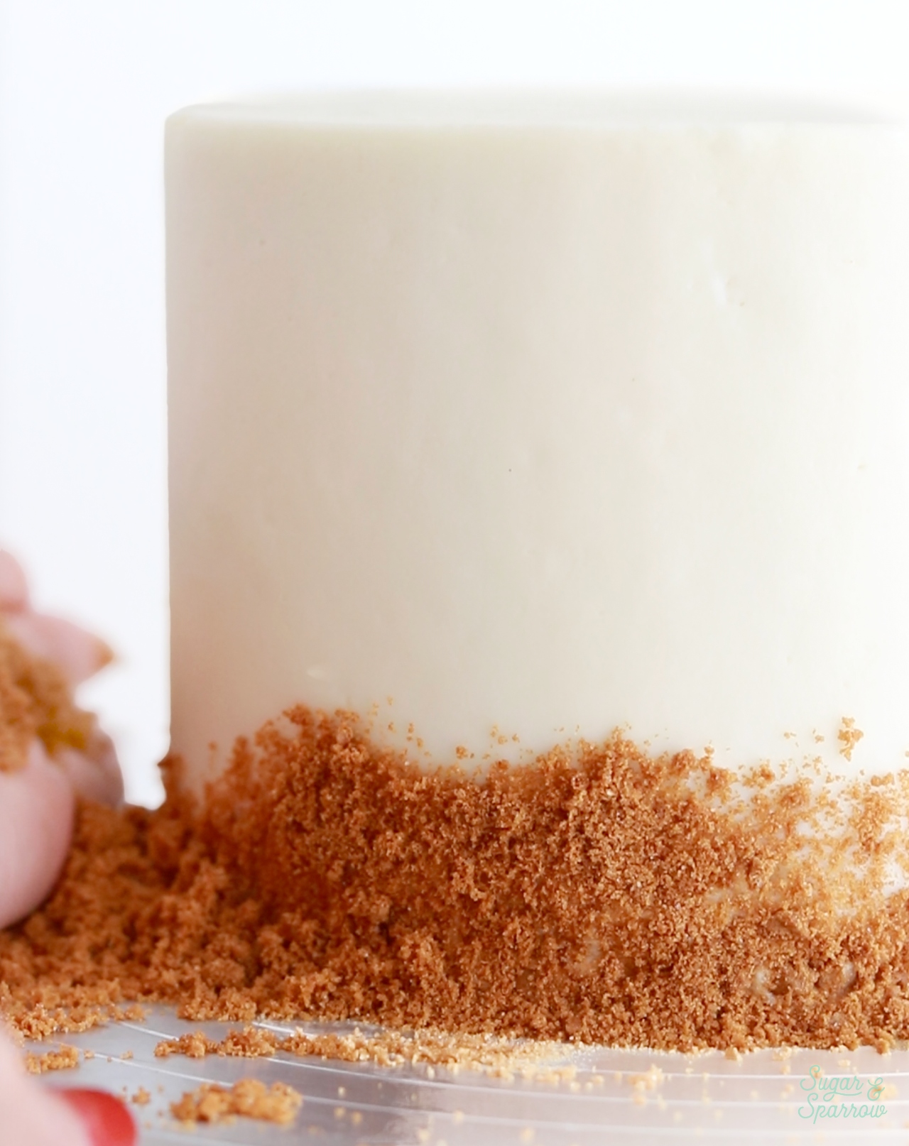pressing biscoff cookie crumbs onto cake