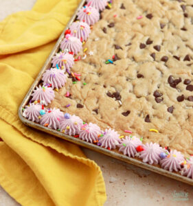 decorating a cookie cake with buttercream and sprinkles