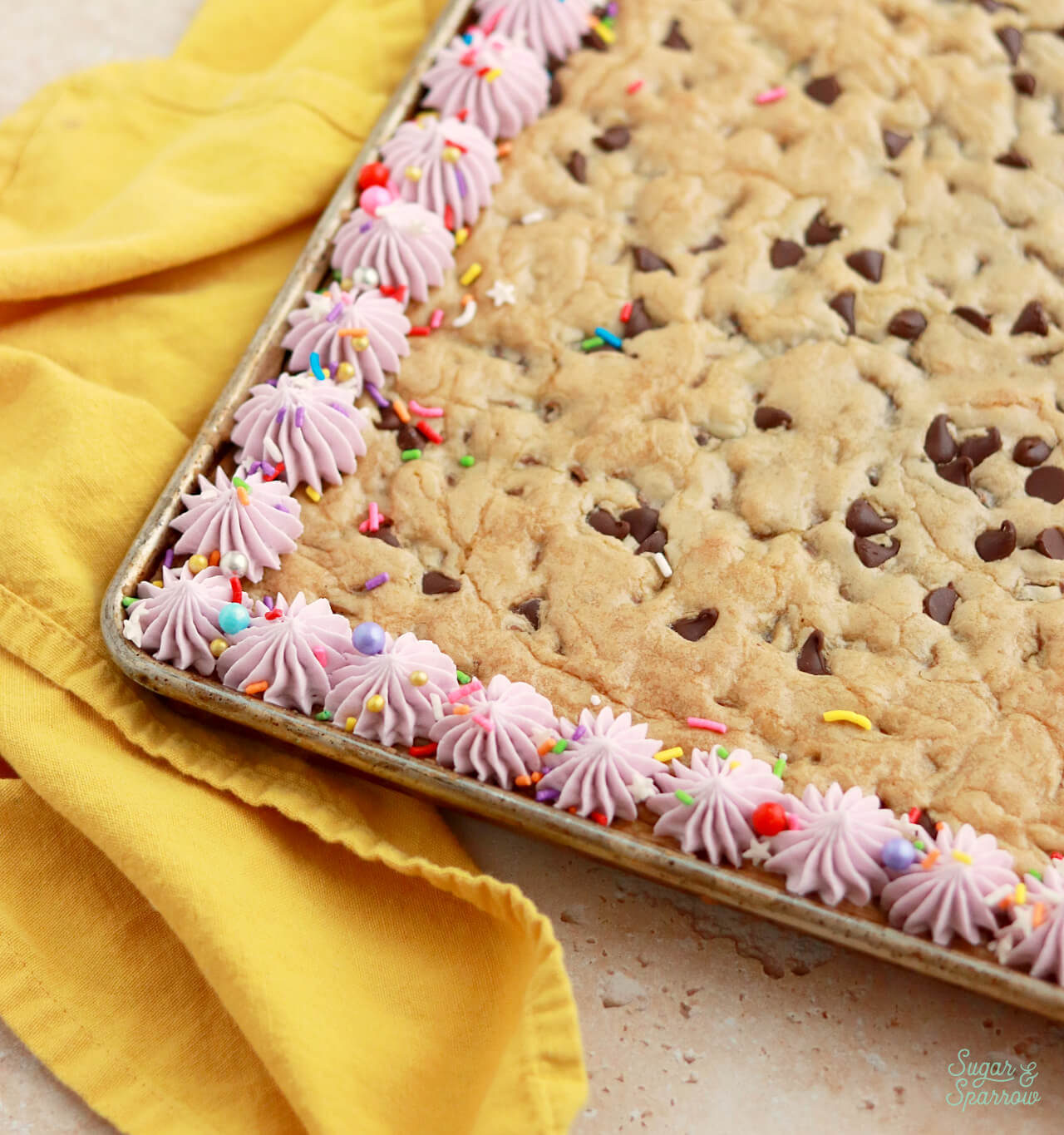 decorating a cookie cake with buttercream and sprinkles