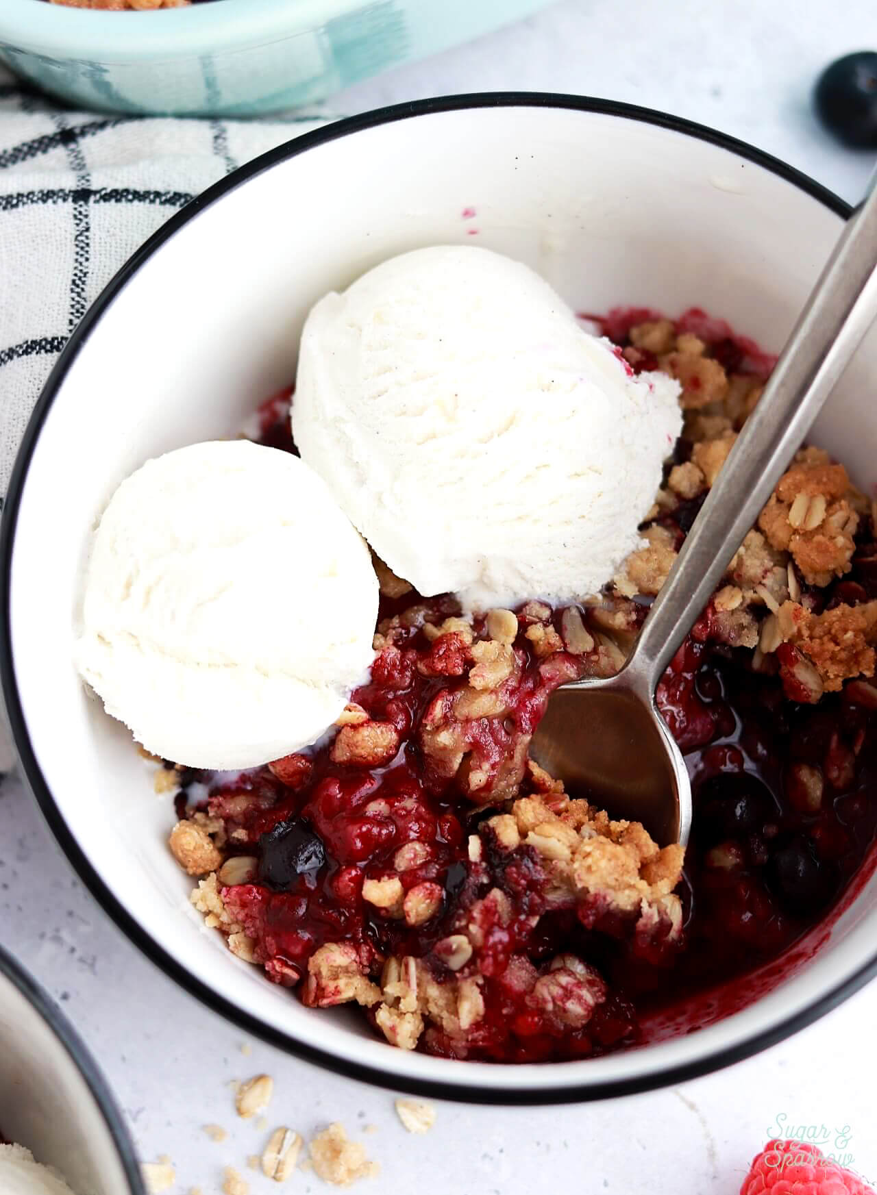 berry crisp recipe in bowl with vanilla ice cream