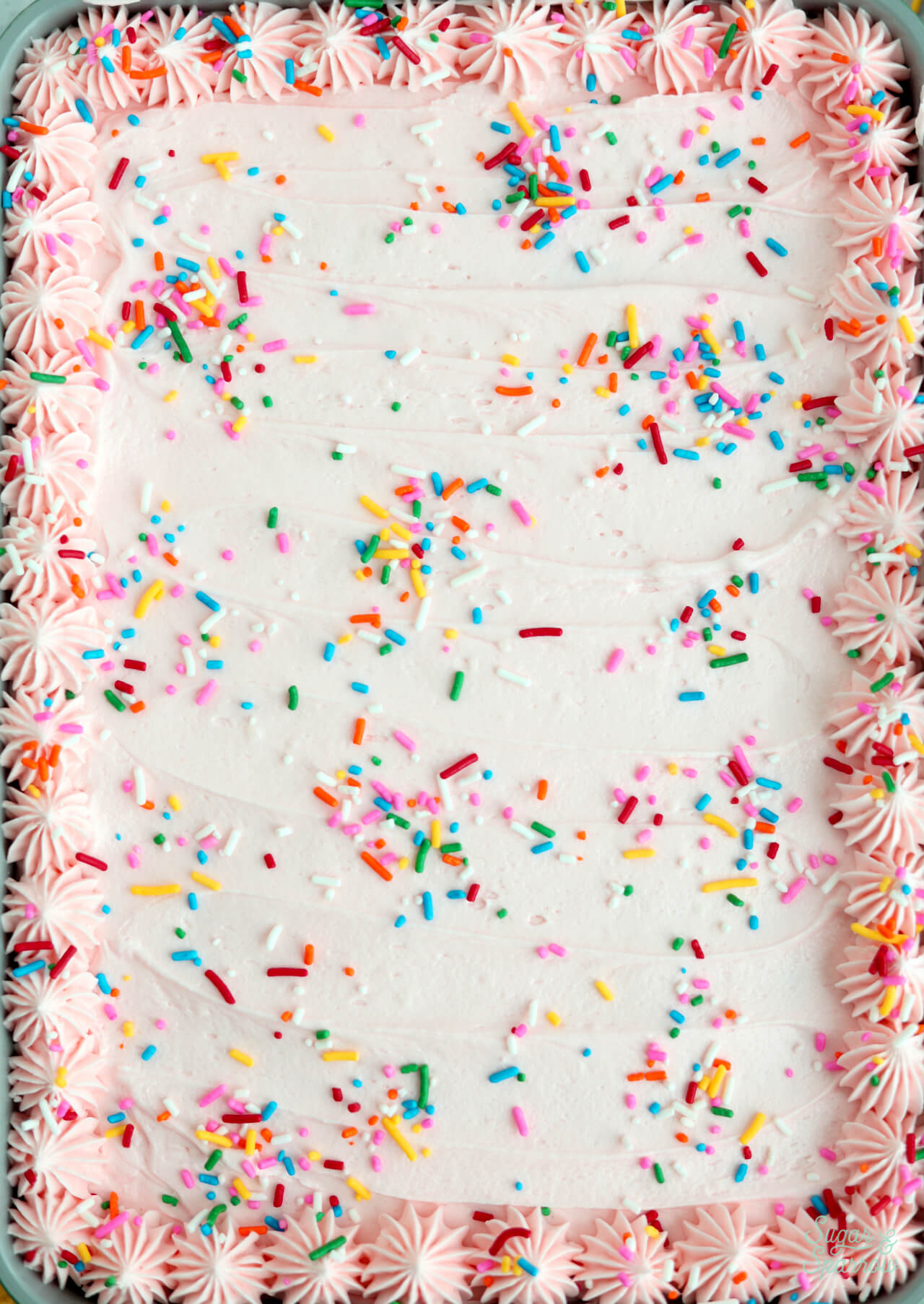 pink frosting with sprinkles on a sheet cake