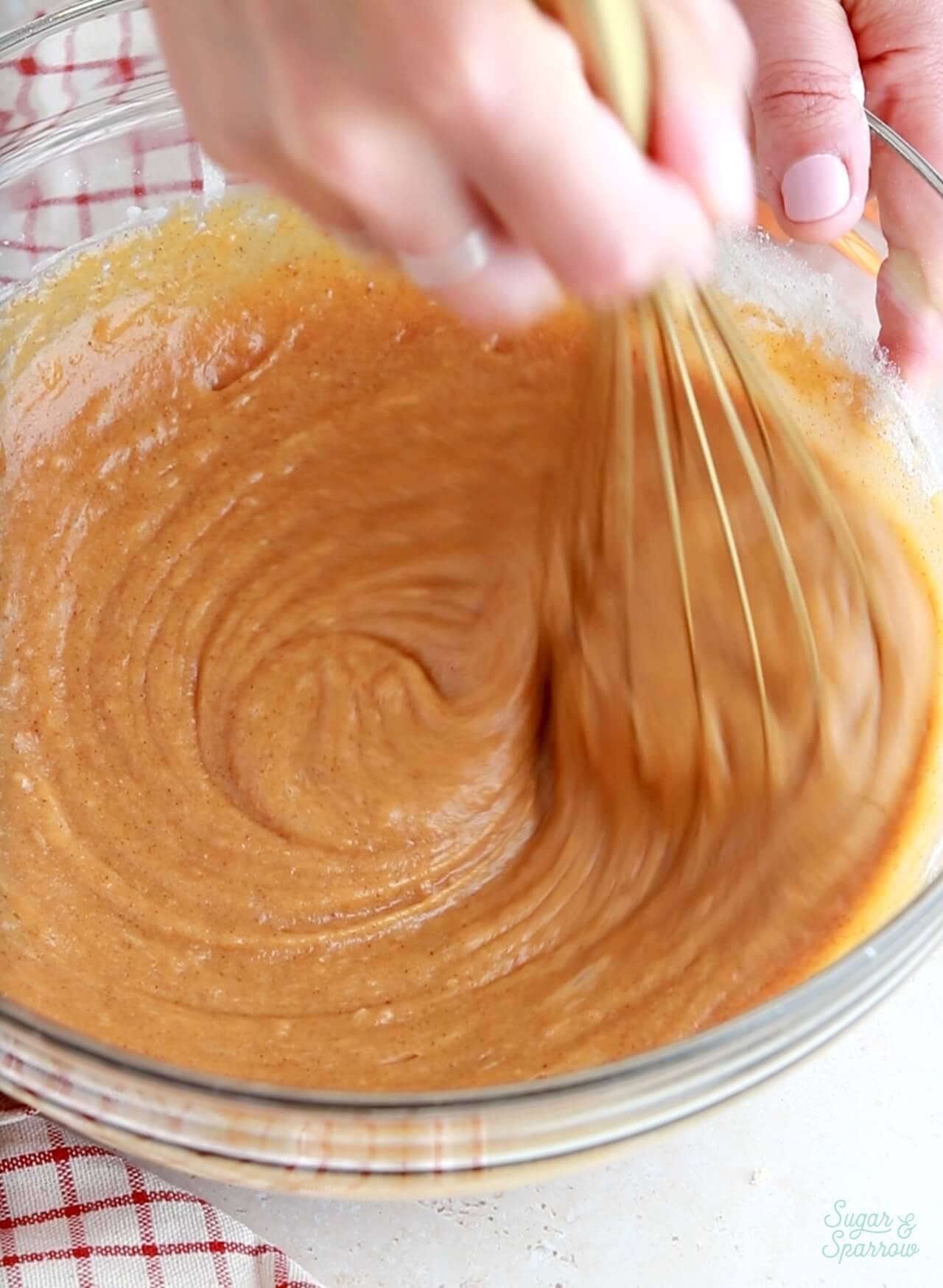 whisking pumpkin cupcake batter in a glass bowl