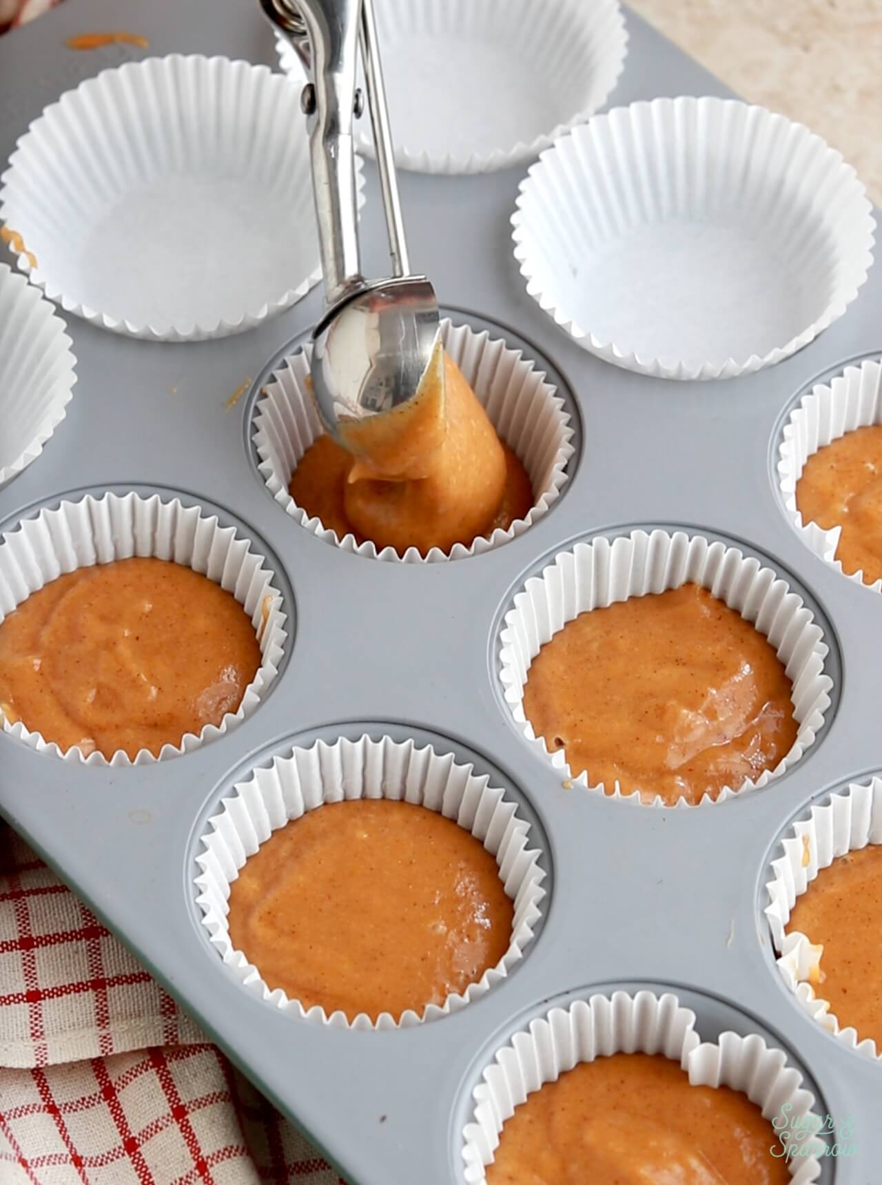 scooping pumpkin cupcake batter into a cupcake pan