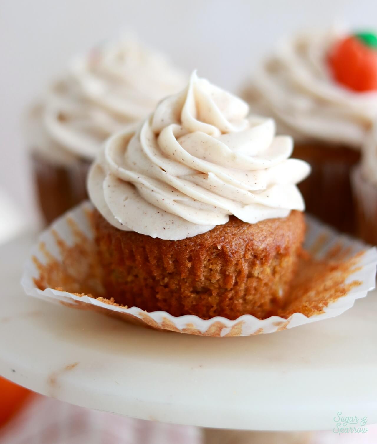 pumpkin cupcakes with cream cheese frosting on a cake stand