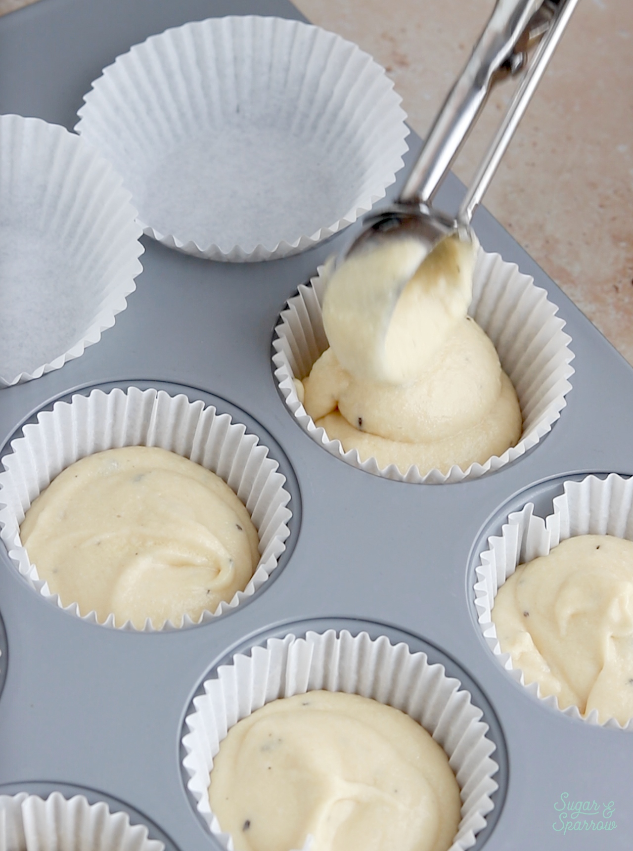 scooping cupcake batter into liners