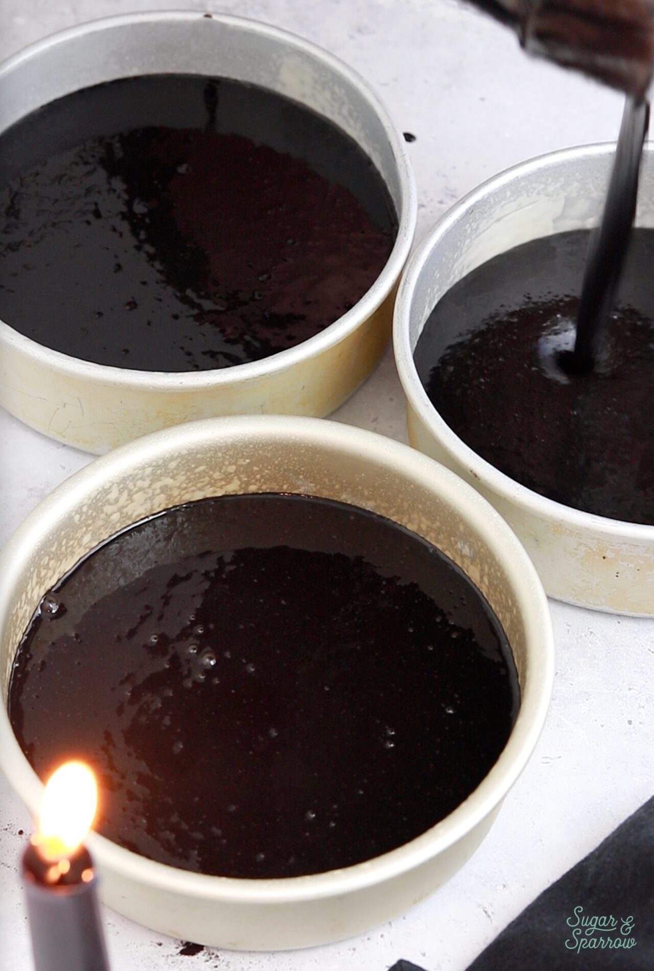 pouring black velvet cake batter into a pan