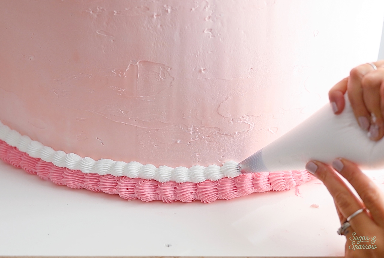 piping a shell border on a fake cake