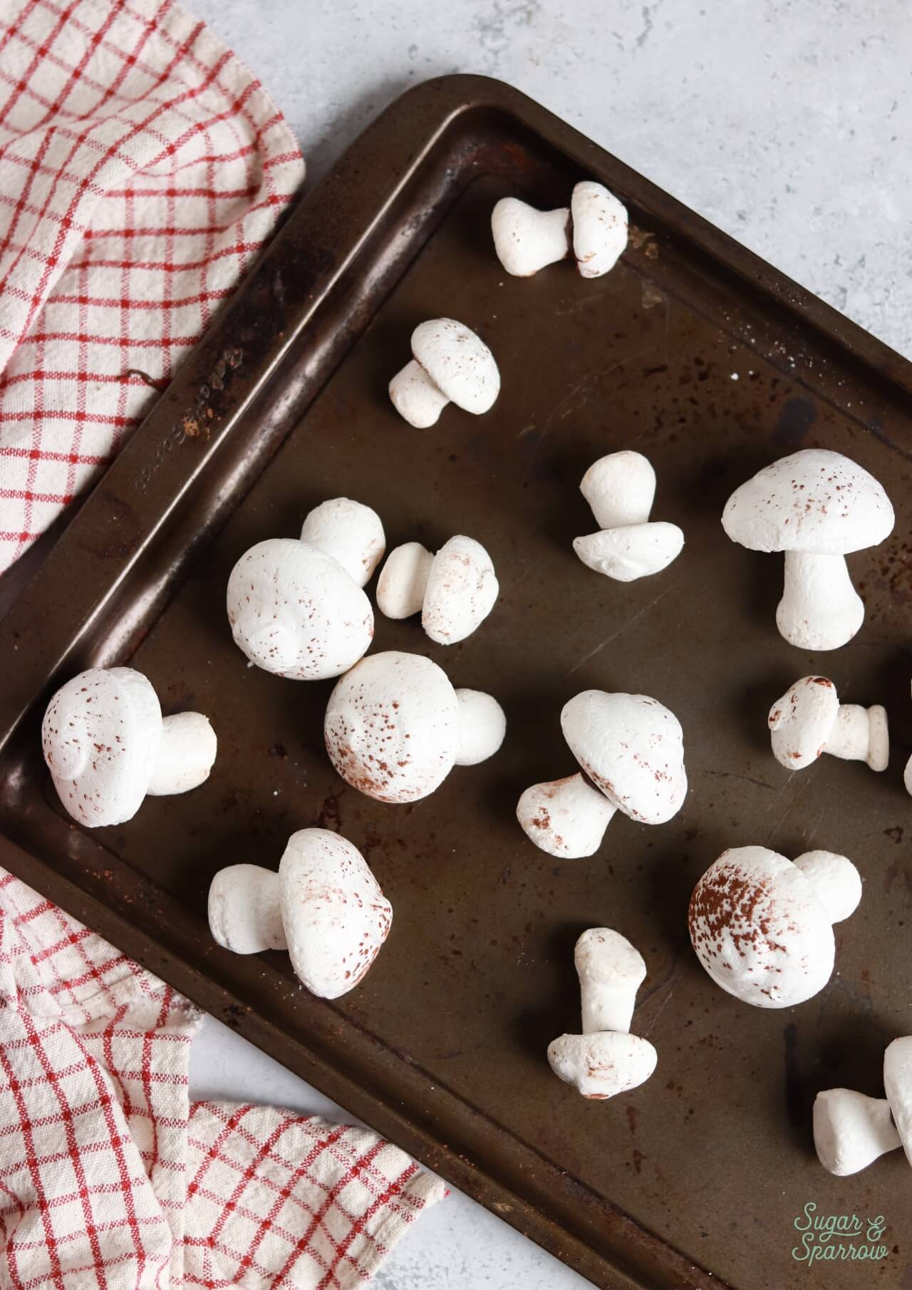assembled meringue mushrooms on a baking sheet