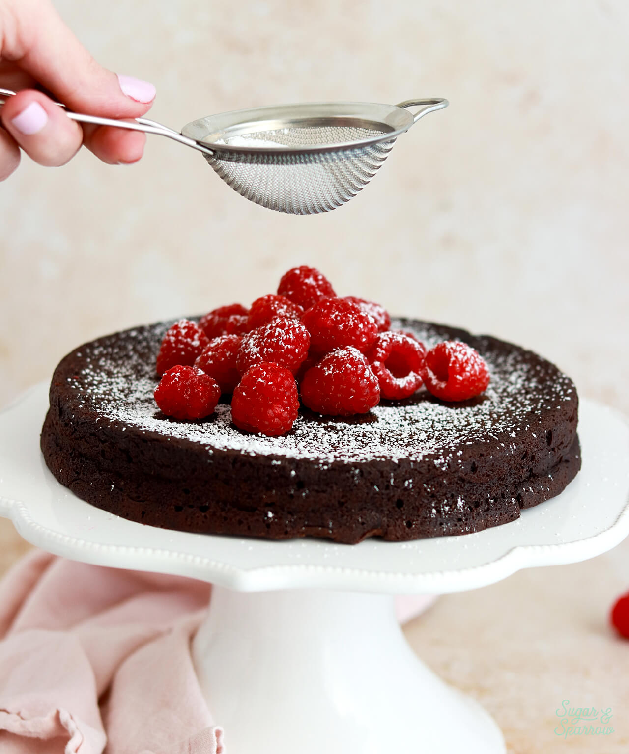 powdered sugar in fine mesh sieve dusting a cake