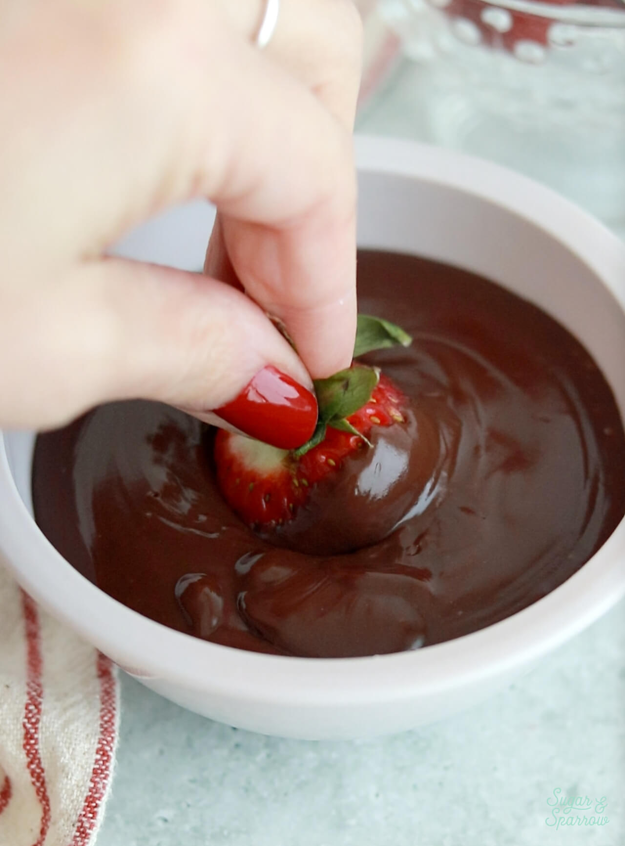 dipping a strawberry in chocolate ganache