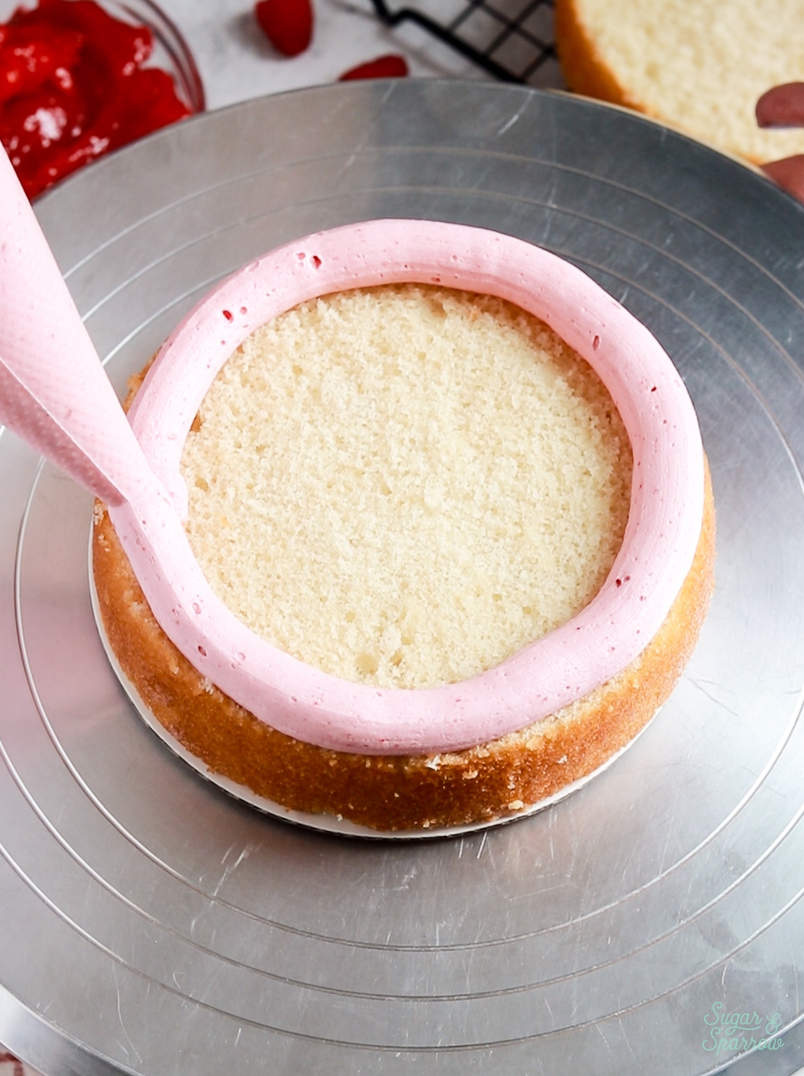 piping a buttercream dam with raspberry buttercream