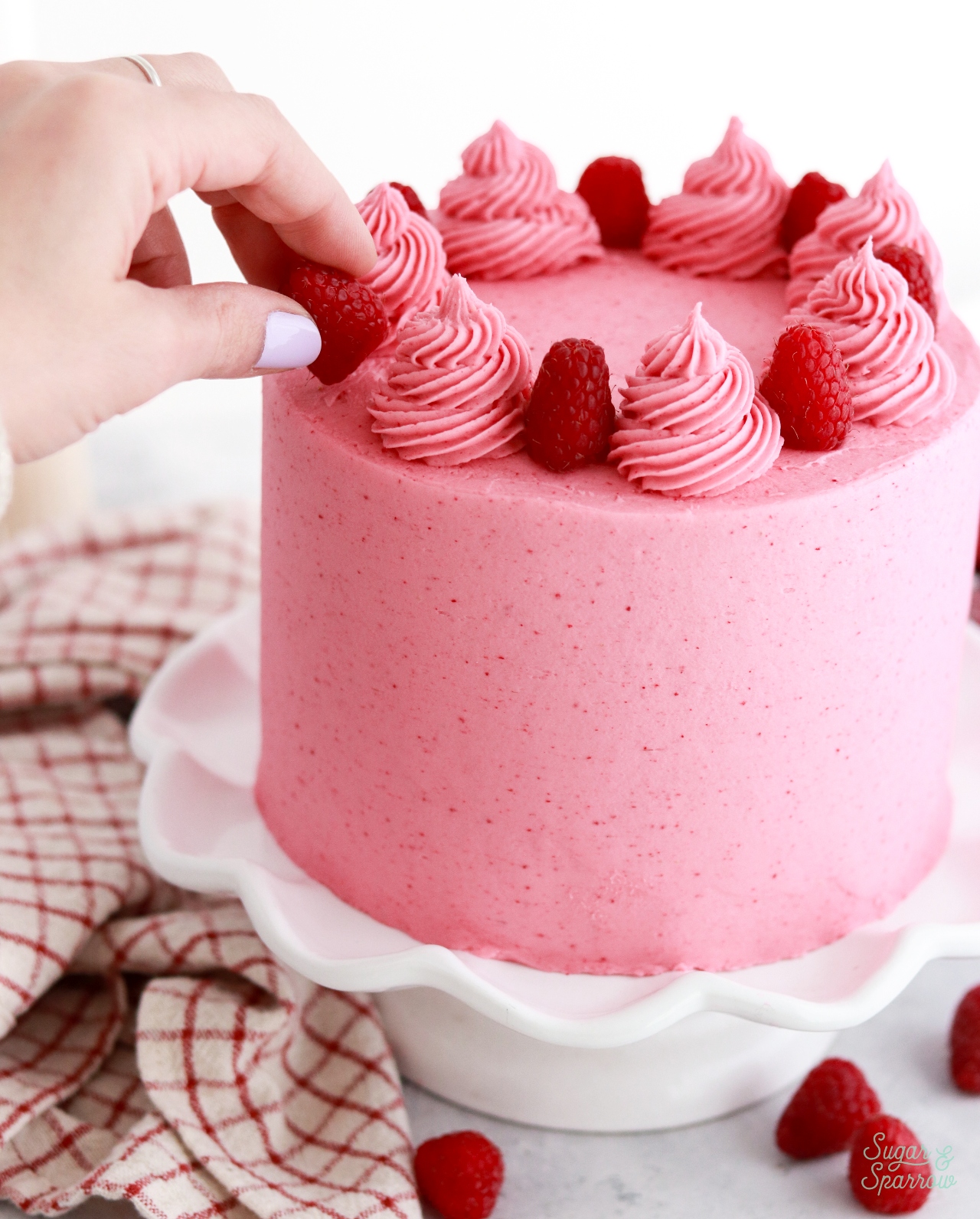 decorating a cake with fresh raspberries