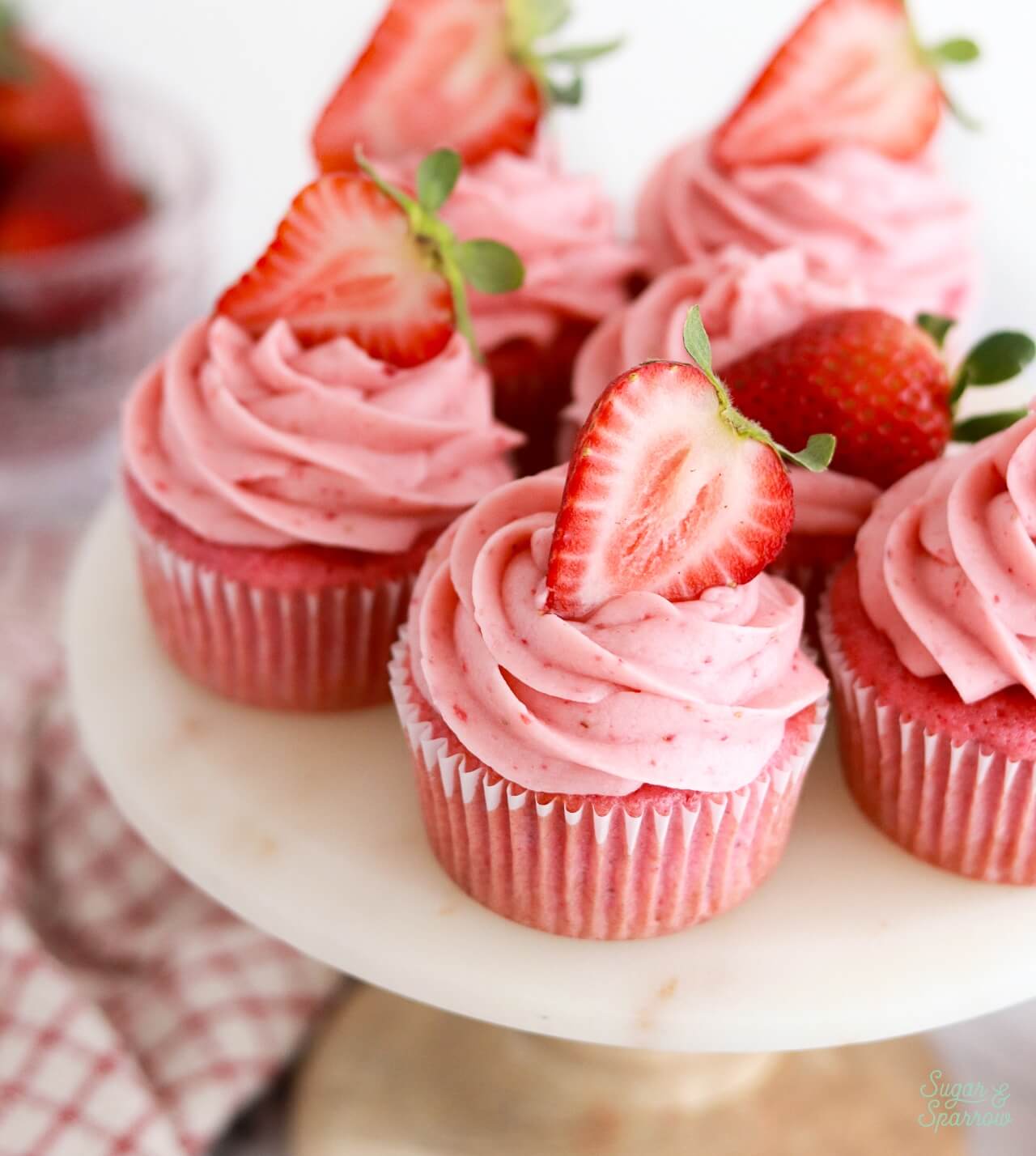 strawberry cupcakes topped with strawberries on a cake stand