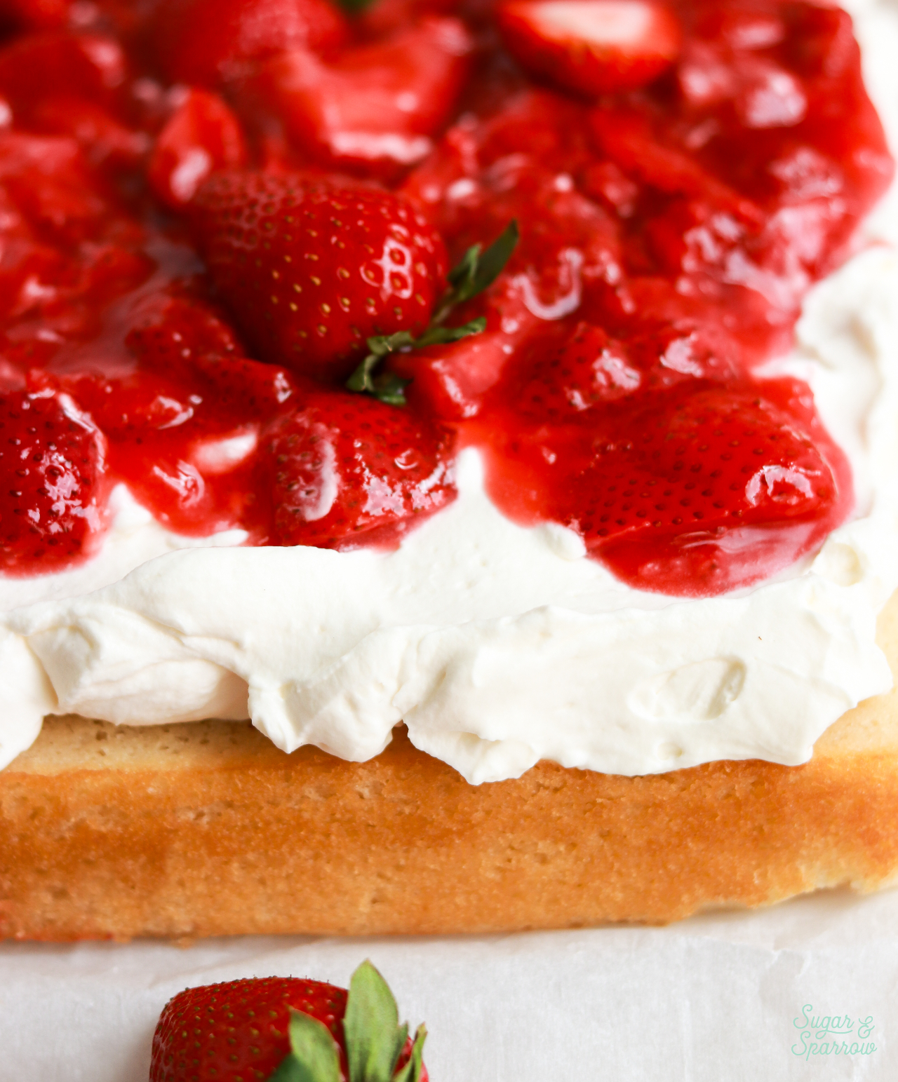 vanilla sheet cake topped with whipped cream cheese frosting and strawberry sauce