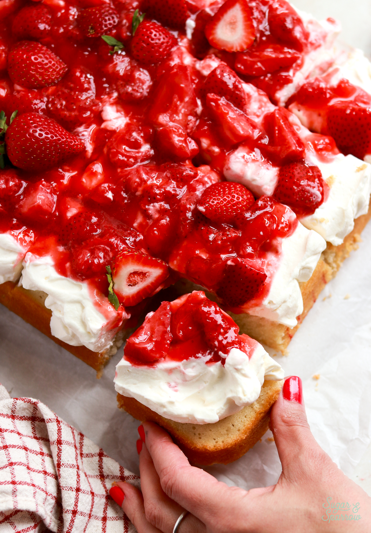 pulling out a slice of strawberry shortcake sheet cake