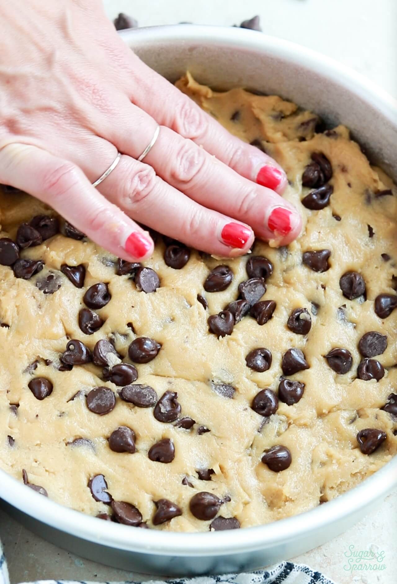 pressing chocolate chip cookie dough into a round cake pan