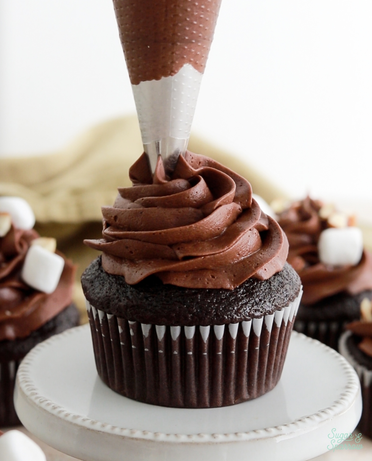 topping cupcakes with chocolate buttercream swirl