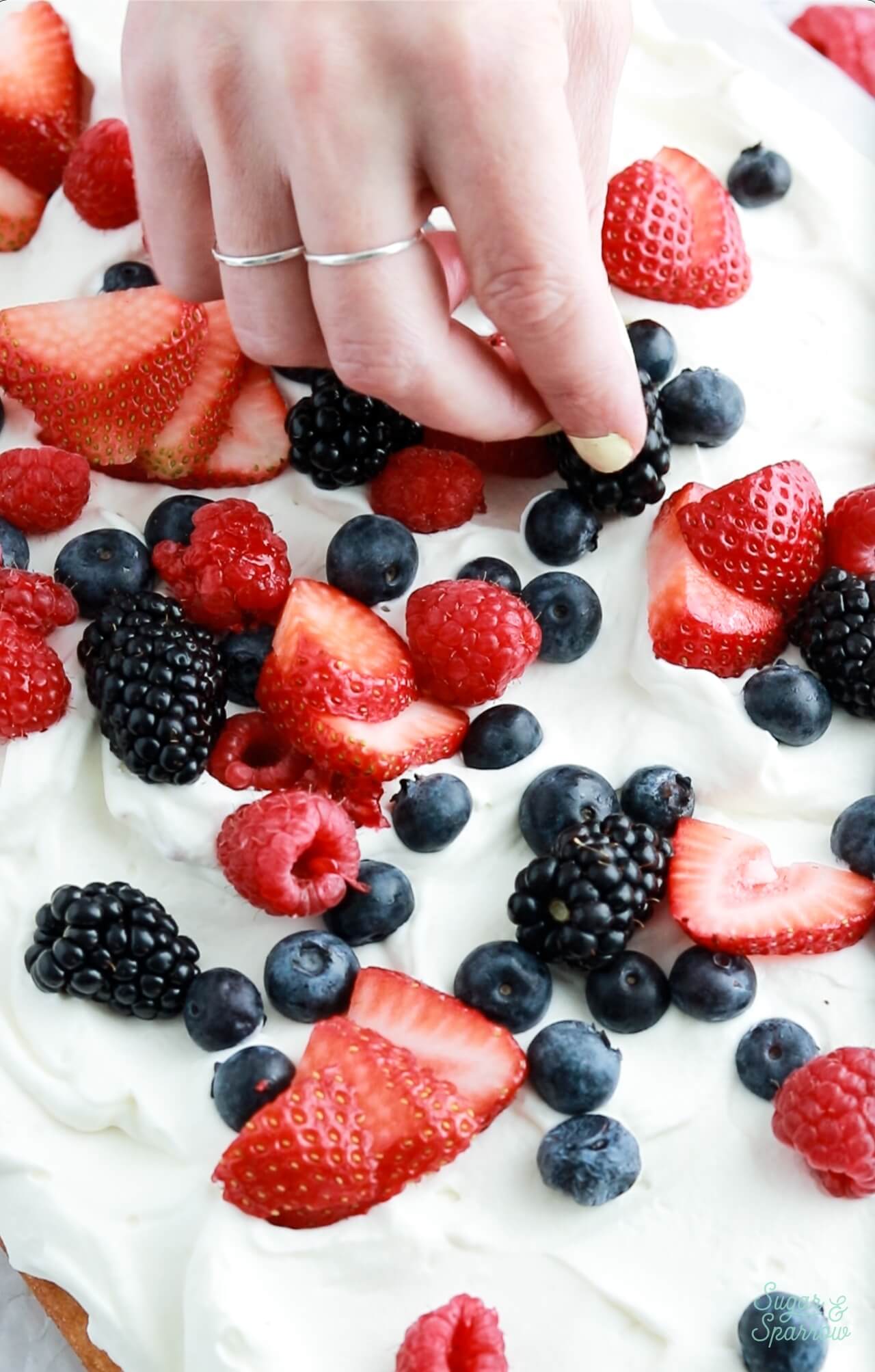 adding berries on top of vanilla cake