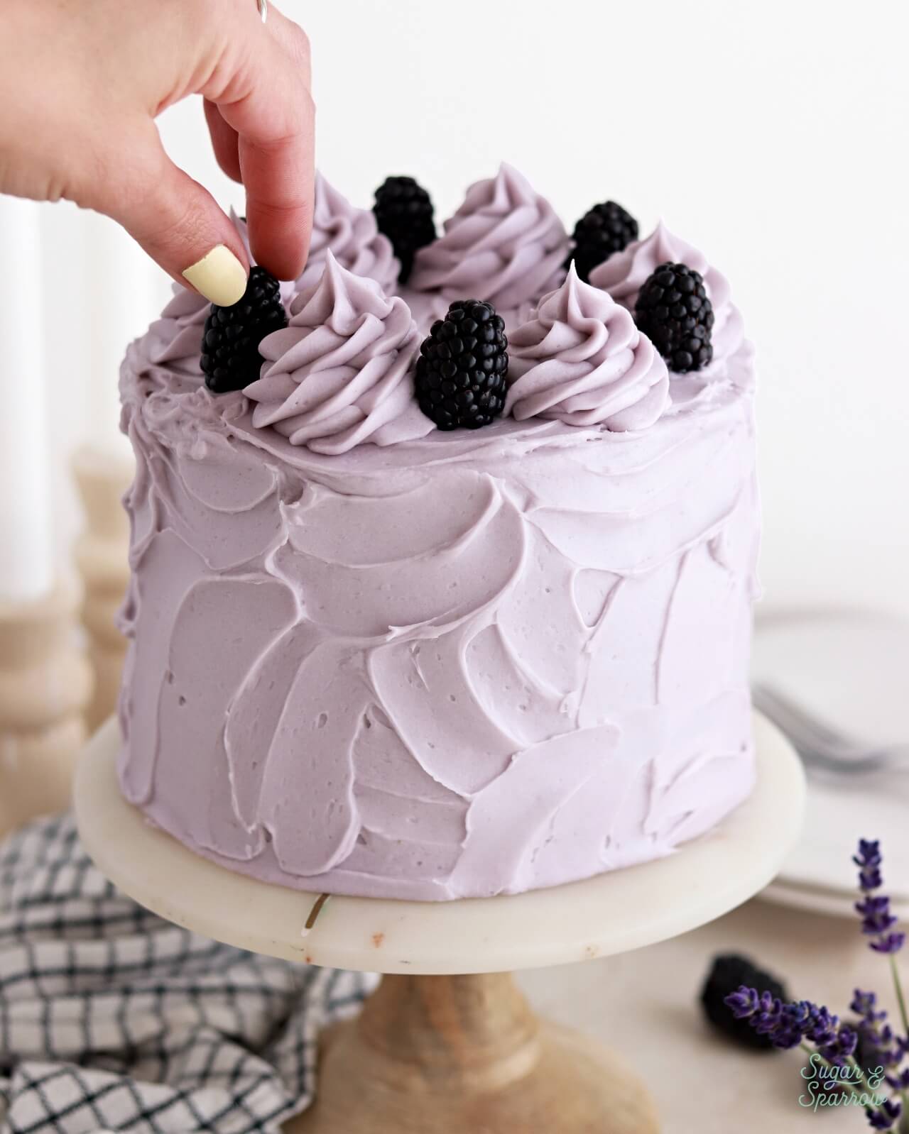 decorating a lavender cake with blackberries