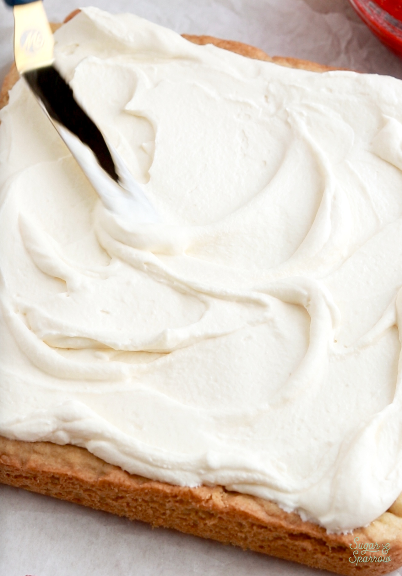 sugar cookie bars topped with whipped cream frosting