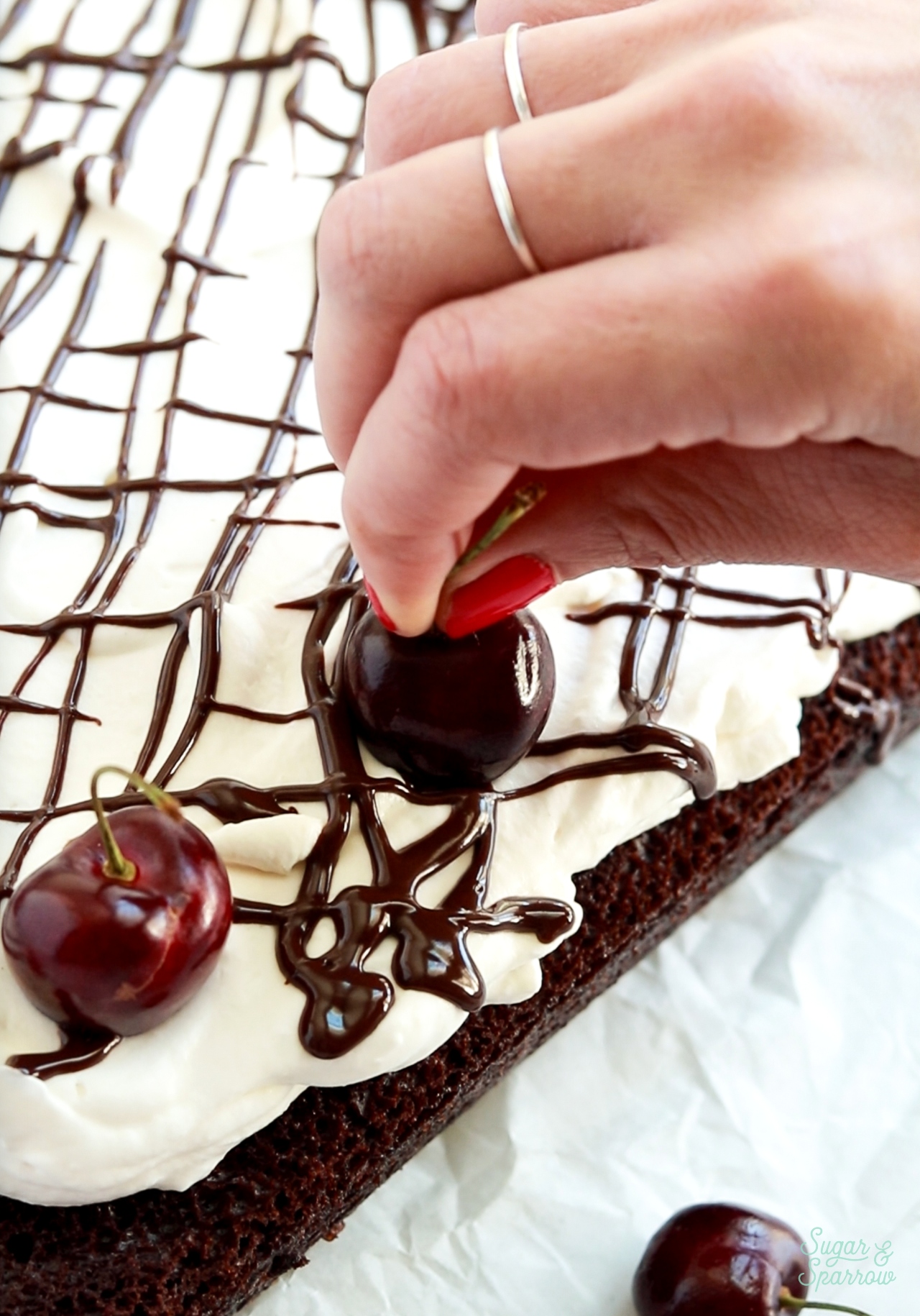 adding cherries around border of sheet cake