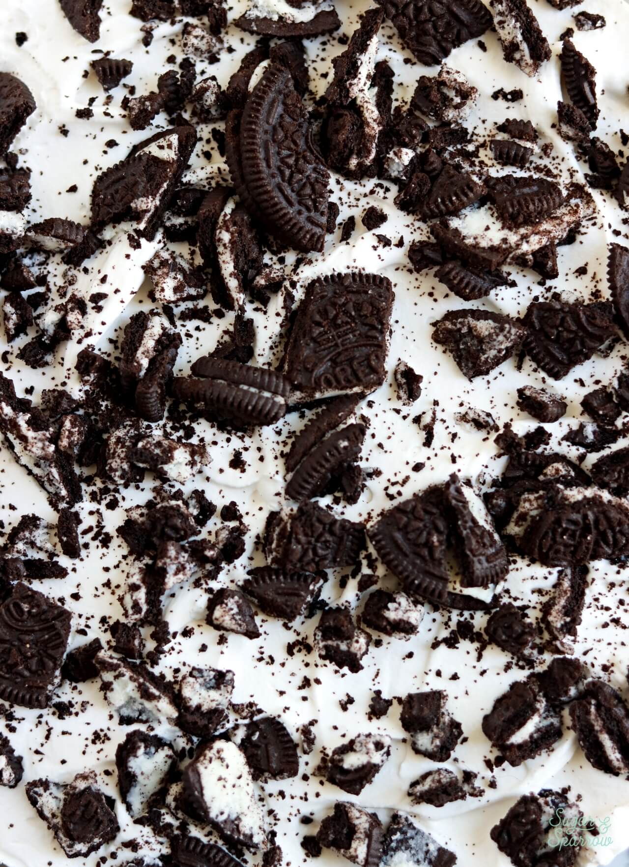ice cream cake topped with whipped cream and oreos