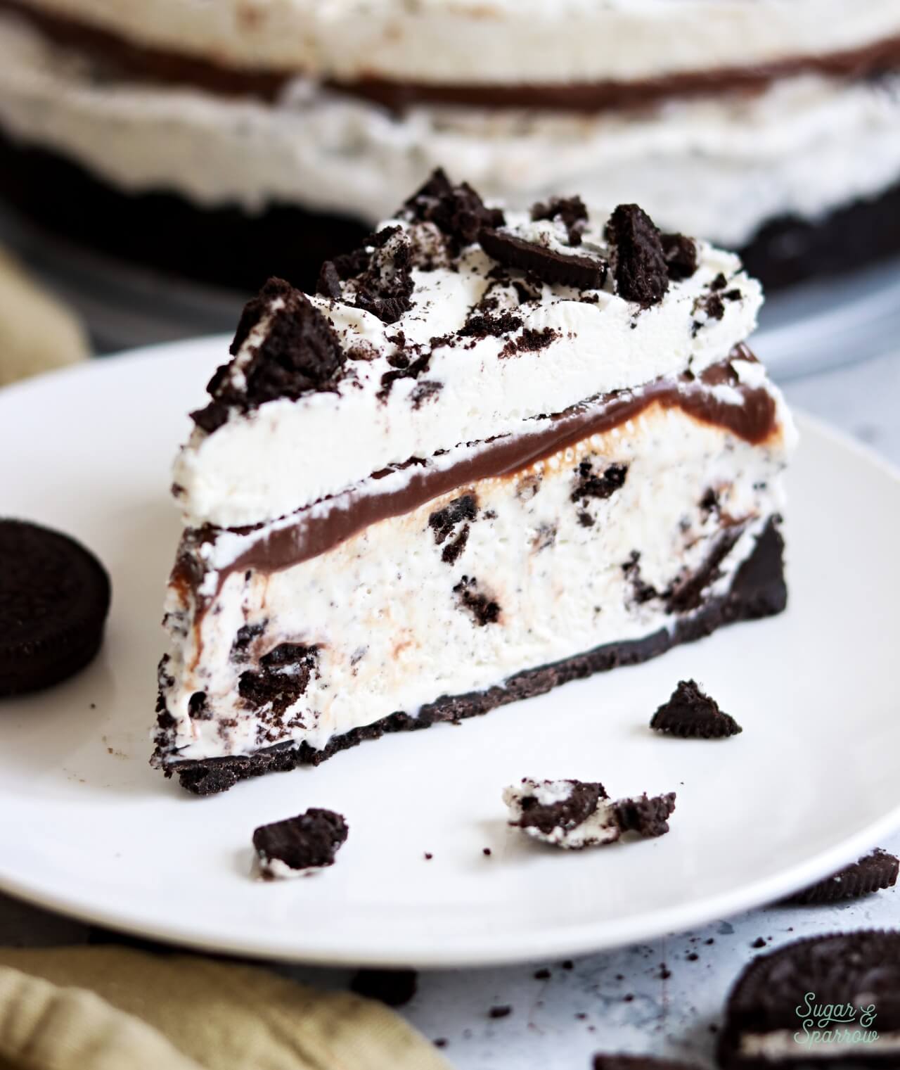 cookies and cream ice cream cake with oreo cookie crust, hot fudge, and whipped cream frosting