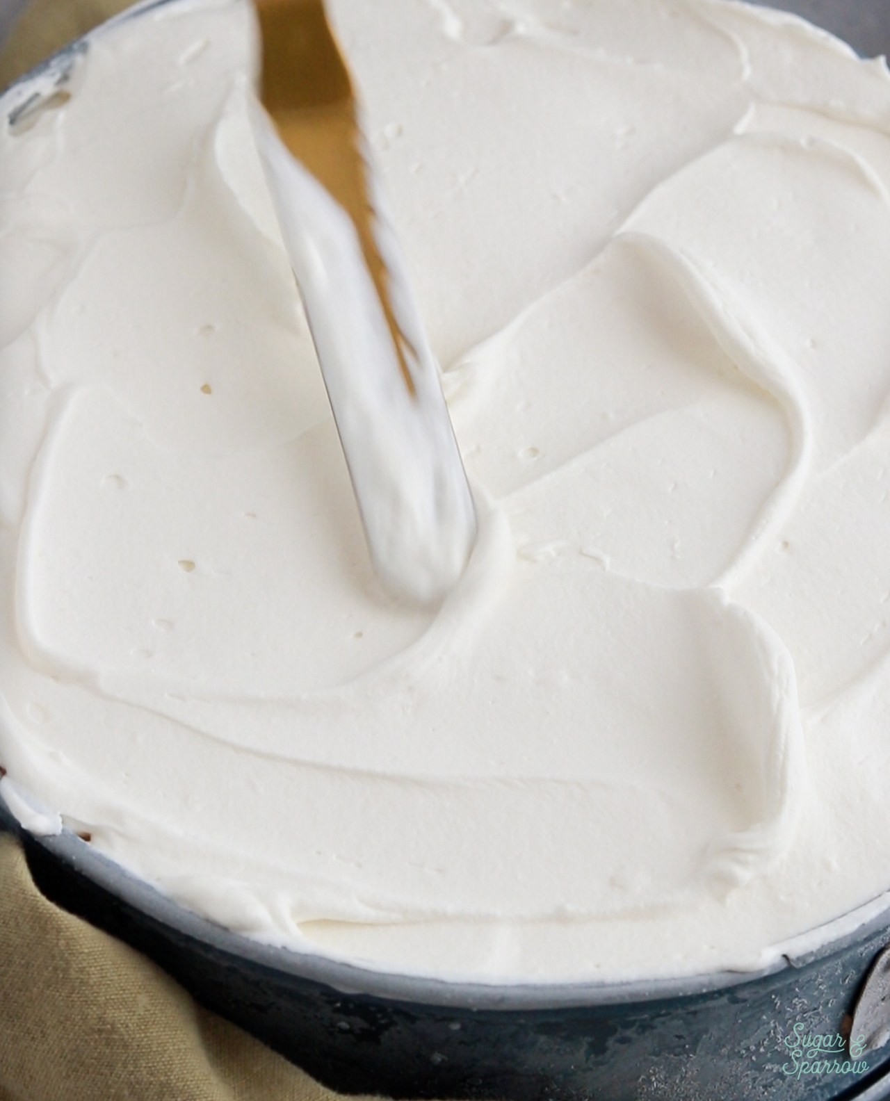 adding whipped cream frosting to ice cream cake