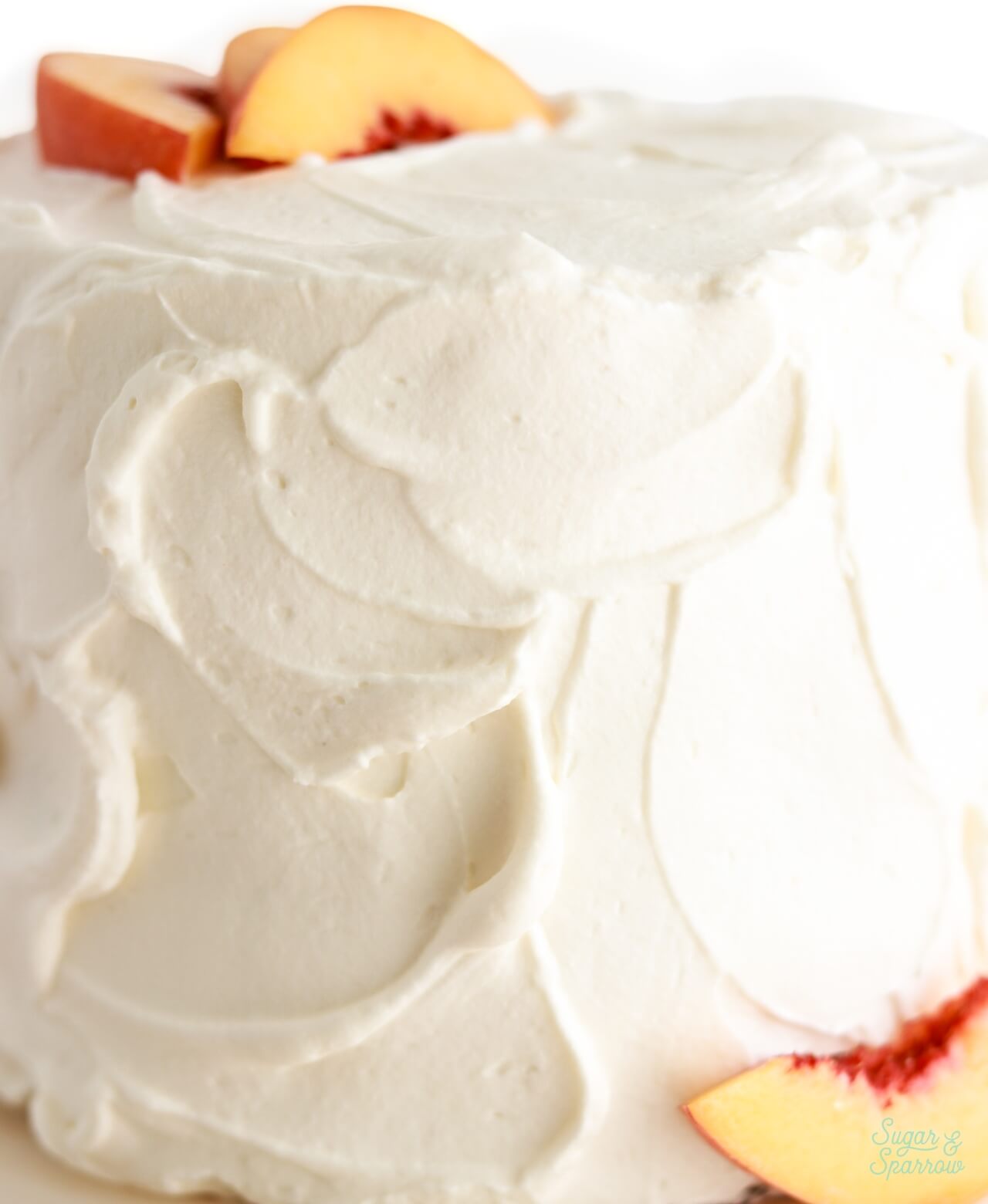 swirls of whipped cream frosting on peaches and cream layer cake