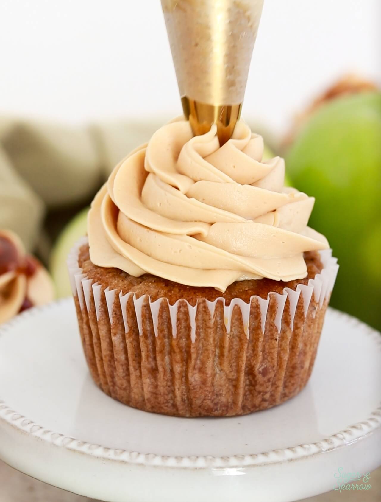 piping salted caramel buttercream onto apple cupcakes