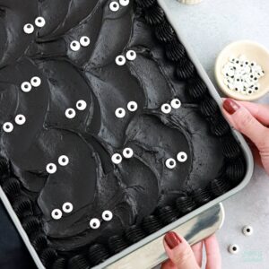 black velvet cake baked in a 9x13 pan decorated with black buttercream and googly eyes