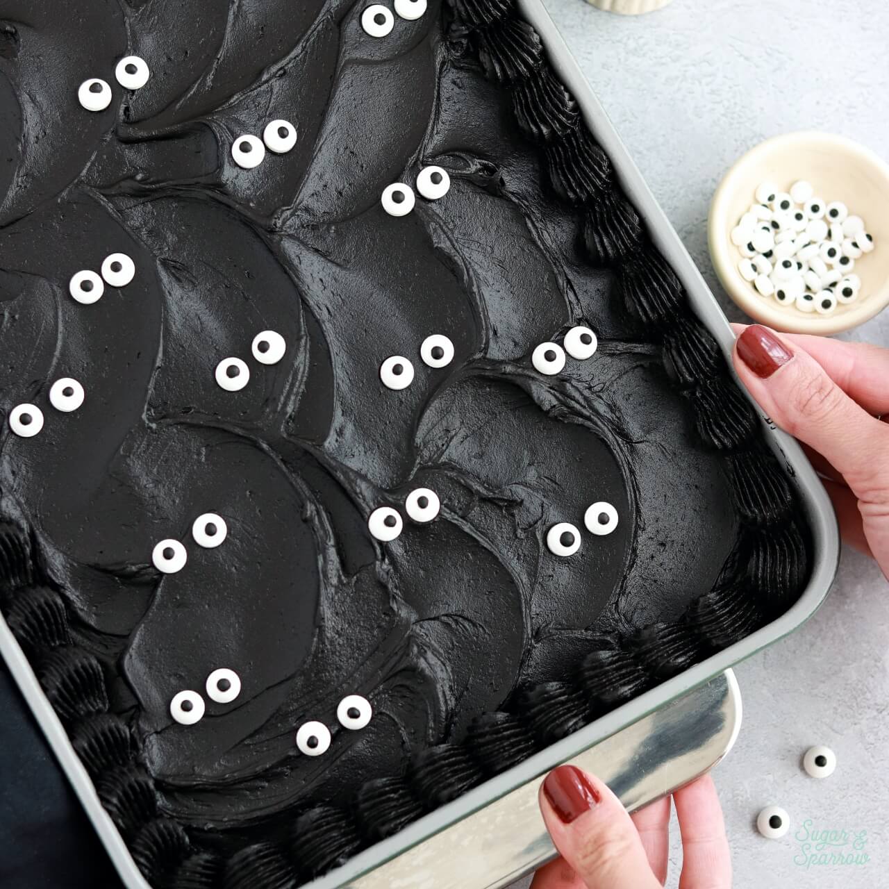 black velvet cake baked in a 9x13 pan decorated with black buttercream and googly eyes